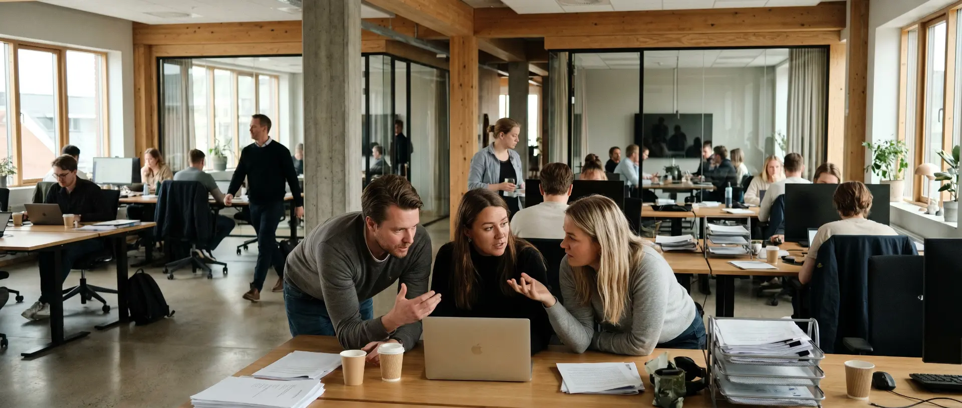 Colleagues in an open-plan office looking at a laptop together